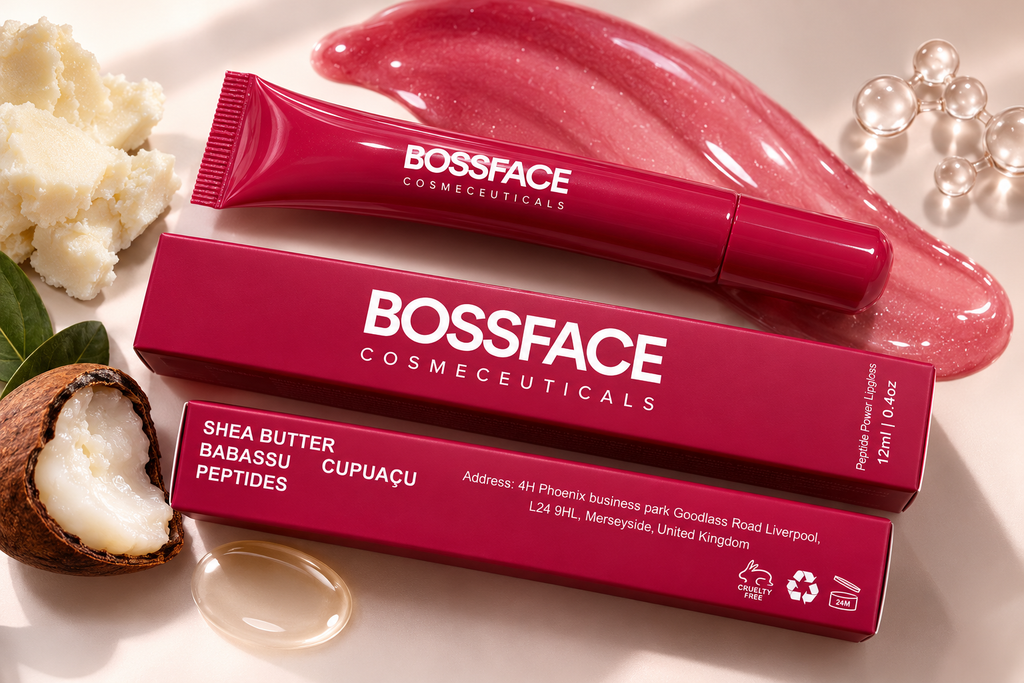 A cosmetic tube and matching box from BOSSFACE COSMECEUTICALs, labeled Shea Butter Babassu Peptides Cupuaçu, arranged on a light beige surface with coconut, cream, and glossy pink cosmetic swatches around it.