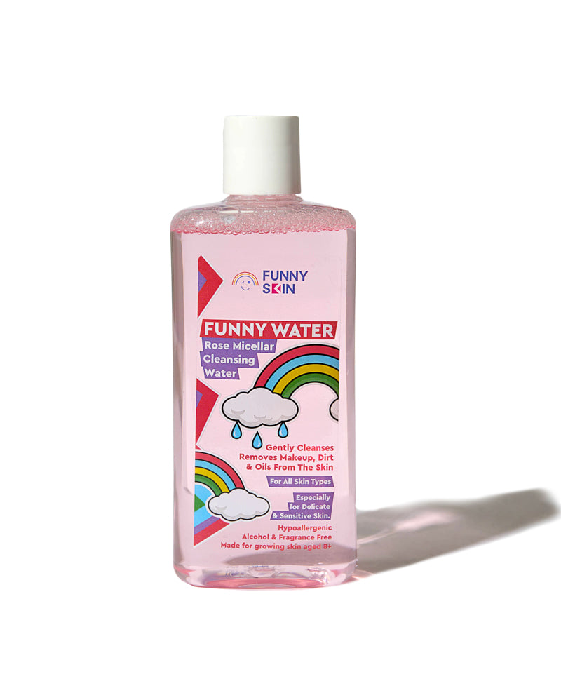 A bottle of Funny Skin 'Funny Water' Rose Micellar Cleansing Water, featuring a pink liquid inside a clear bottle with a white cap and a colorful label with rainbows and clouds.
