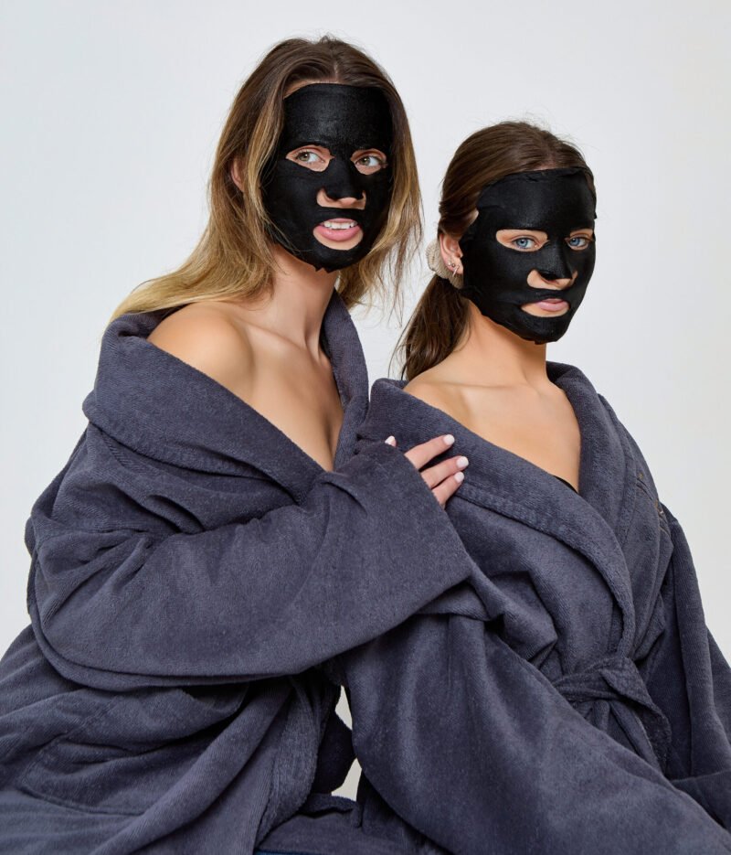 To ladies in wearing grey bathrobes with the BFx Black Crystal Mask on their face
