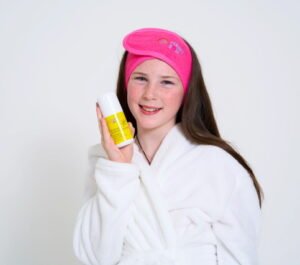 A tween girl holding a yellow bottle of Protect and Play SPF by funny skin