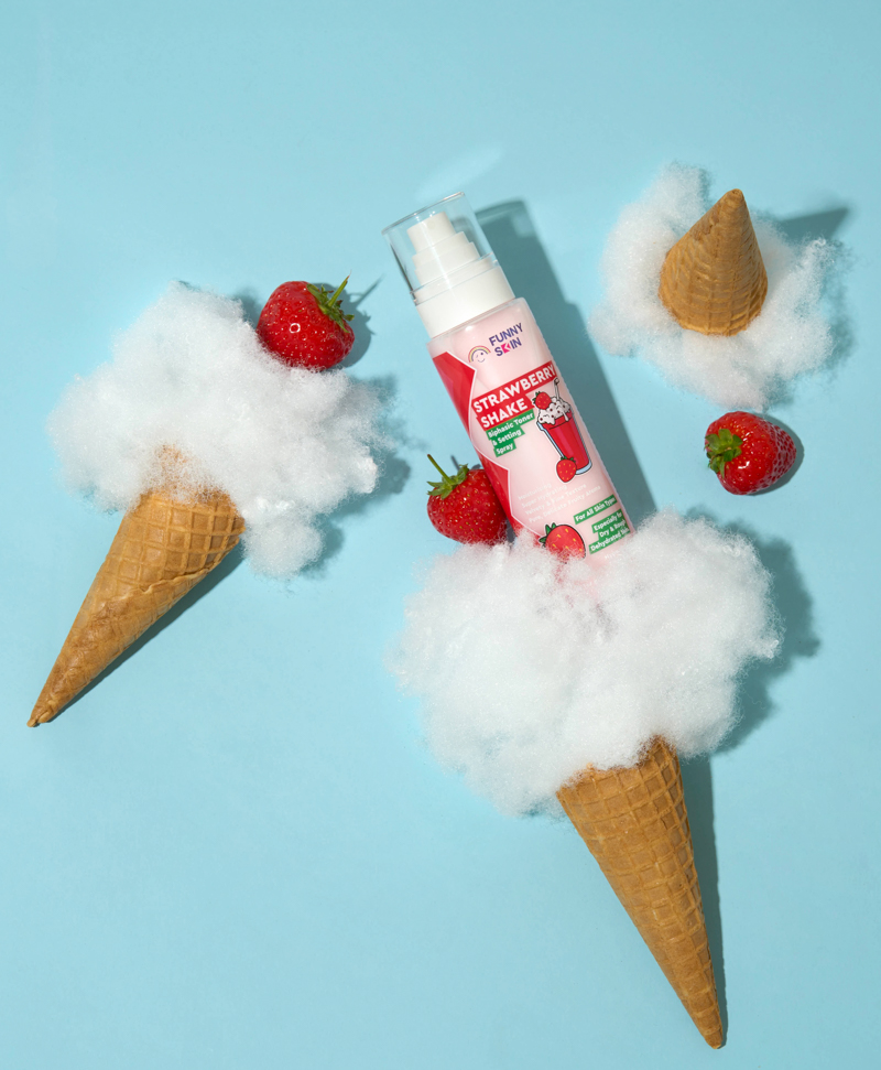 38fs funny skin strawberry shake skincare product lying on a blue floor with strawberries and ice cream cones