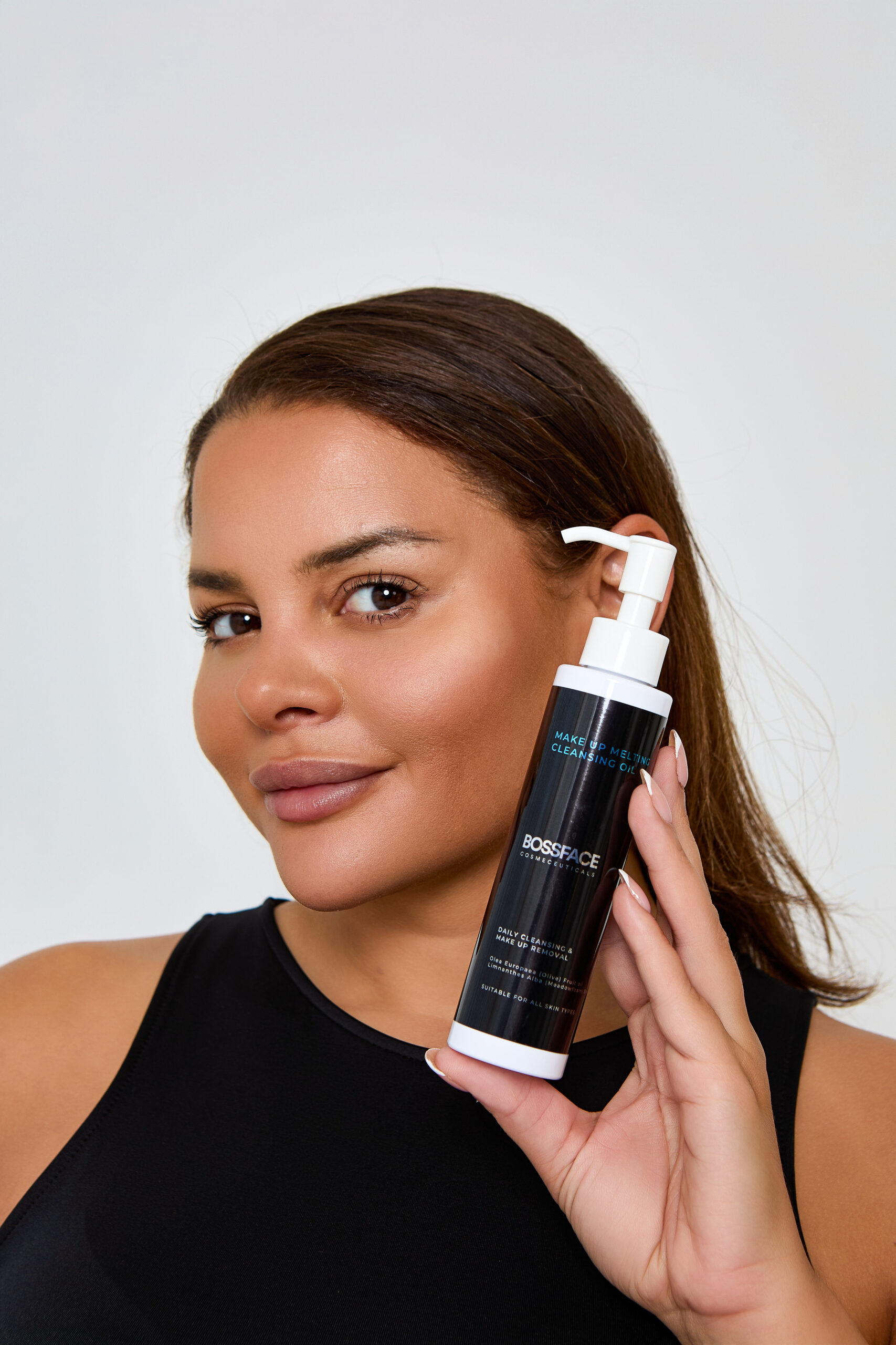 girl holding make up melting cleanser beside her face